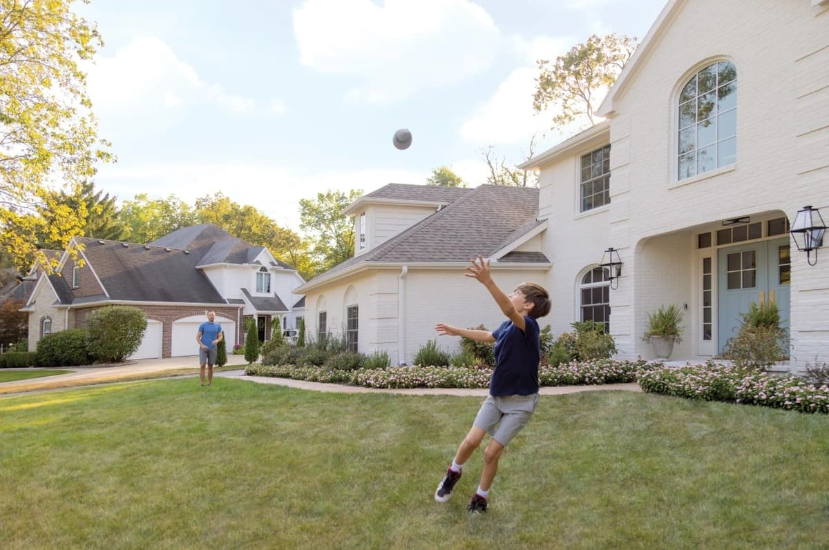 A father and son playing catch in the front yard.