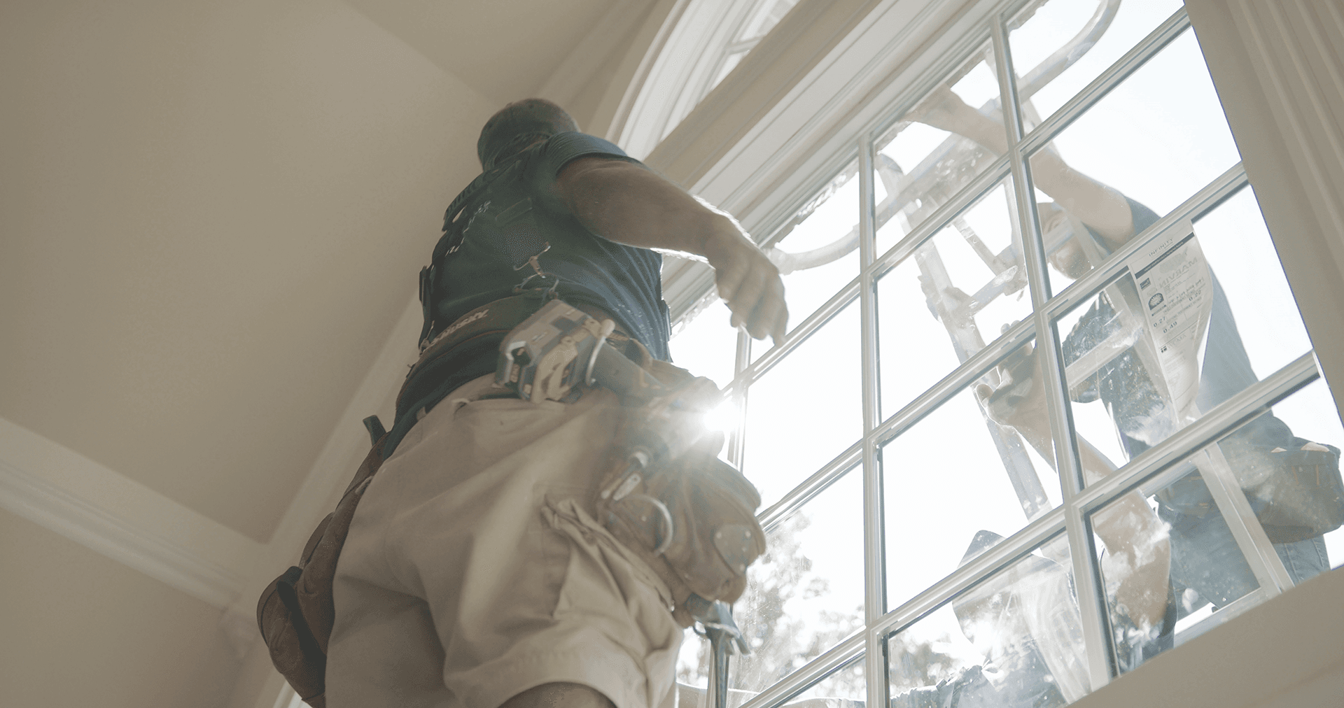 Workers install a white fiberglass replacement window.