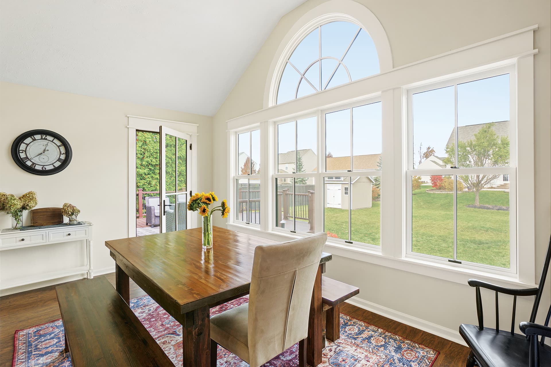 A cream-colored dining room interior with white double hung windows and an arch window with divided lites.