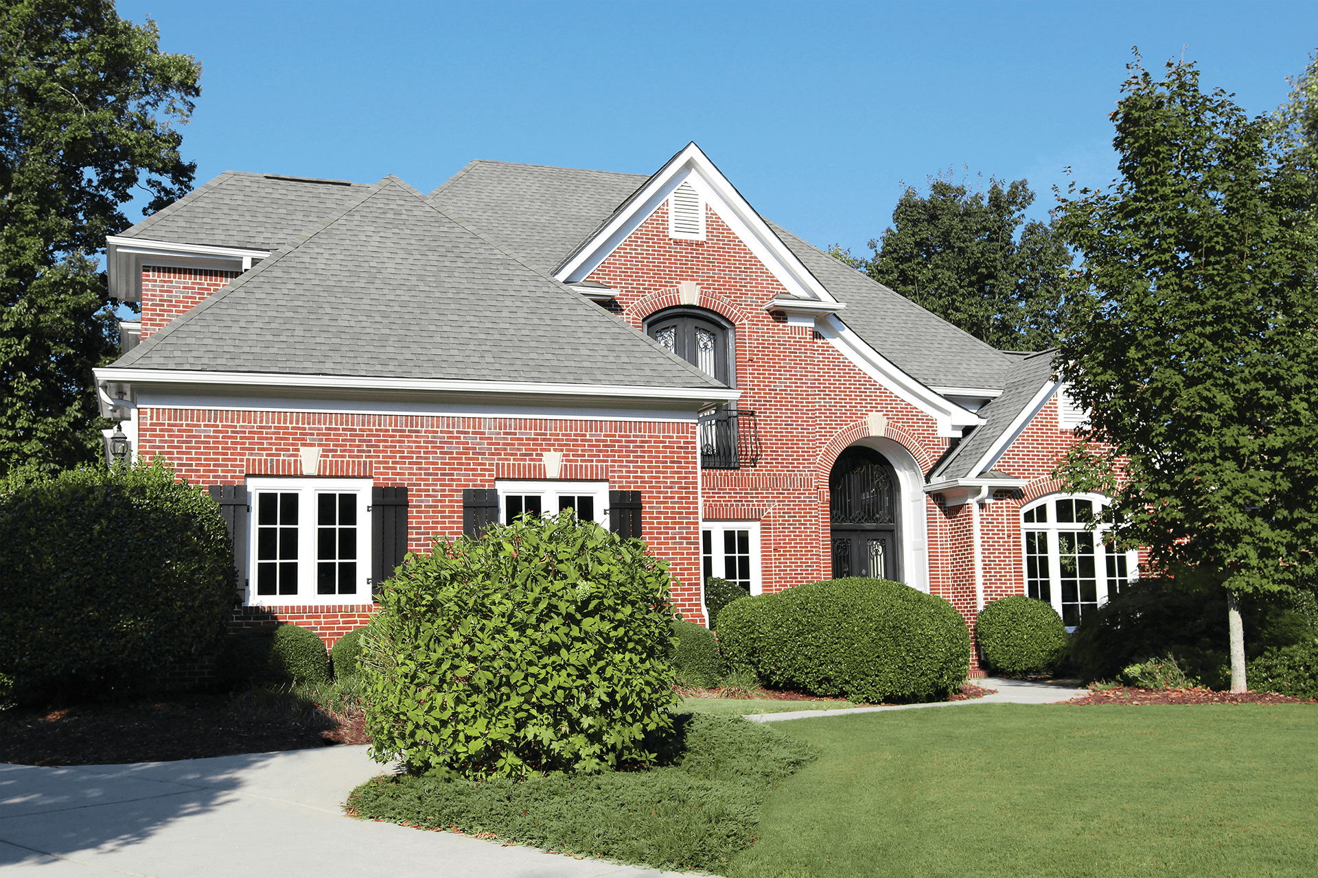 Exterior view of a brick home with white windows and black shutters.