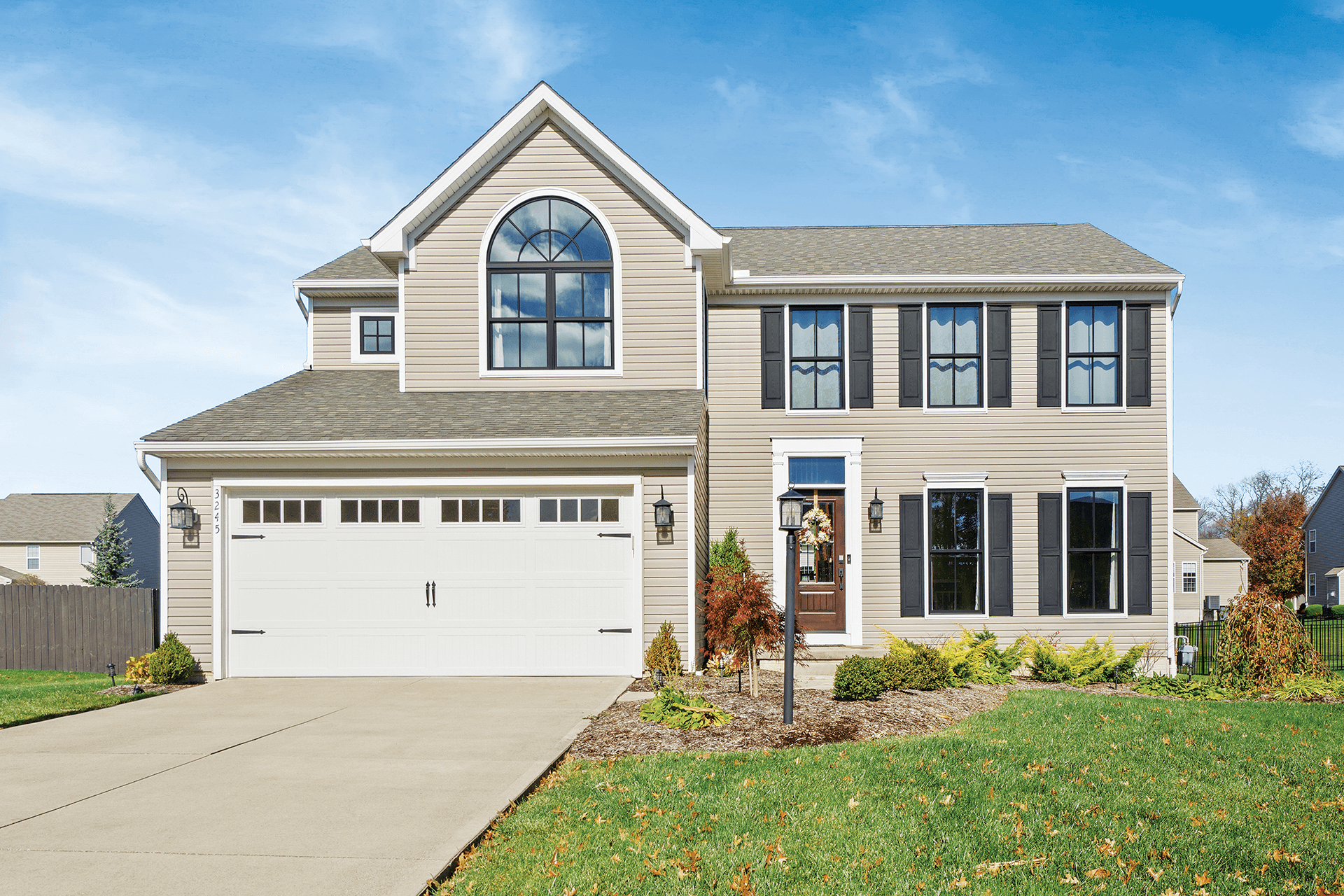 Exterior view of a beige home with black windows and shutters.