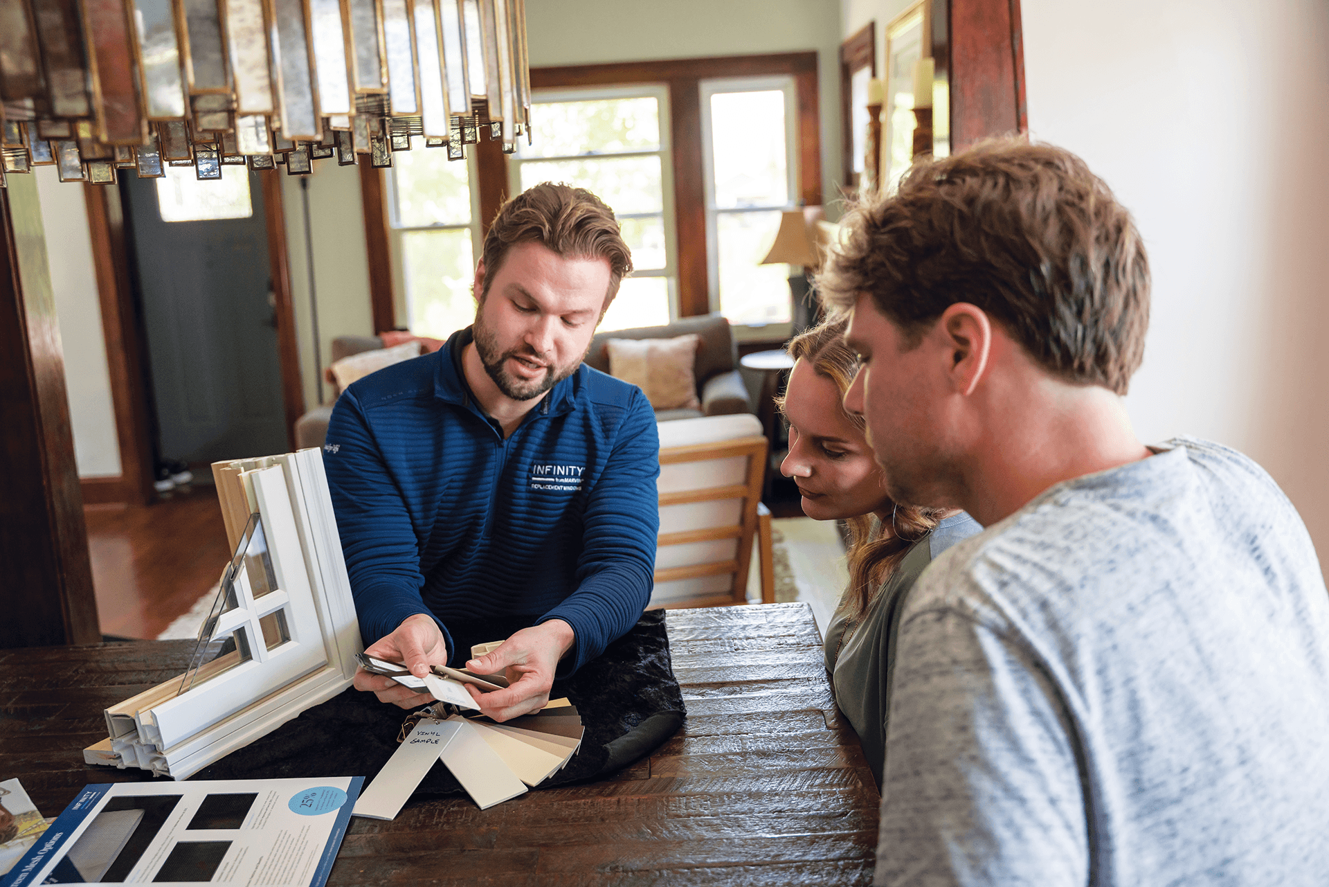 An Infinity from Marvin salesman reviews samples with a couple inside their dining room.