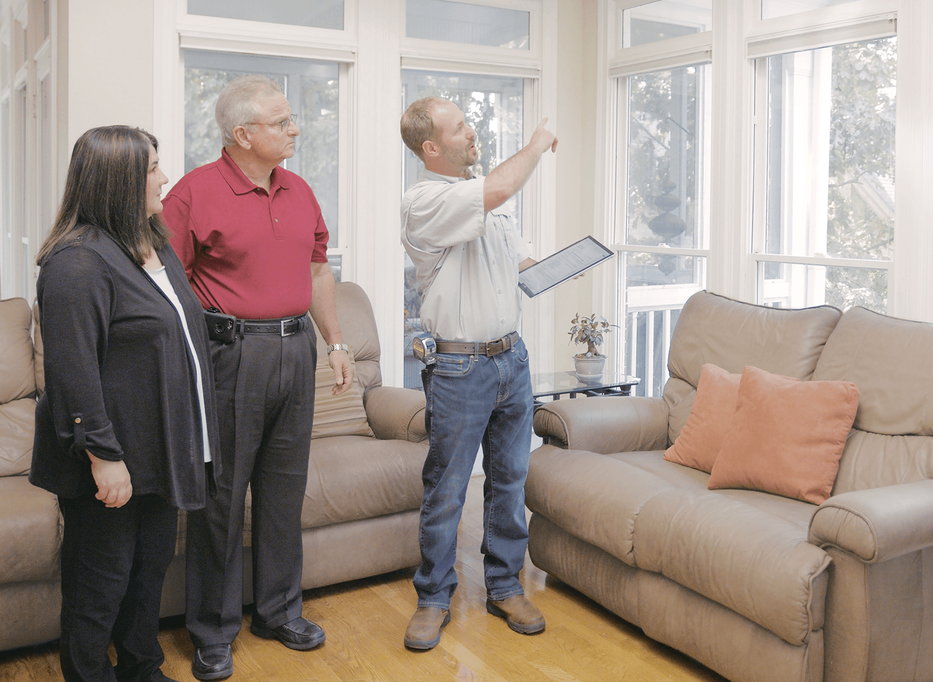 An Infinity windows design consultant points to windows during an appointment with a couple inside their home.