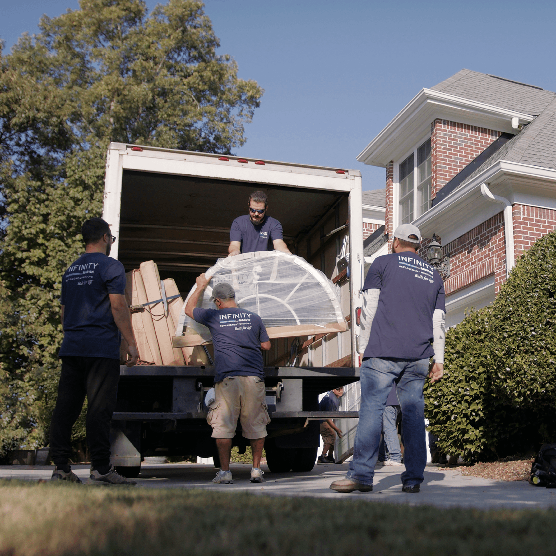 A group of Infinity window installers load a cargo truck with a window.