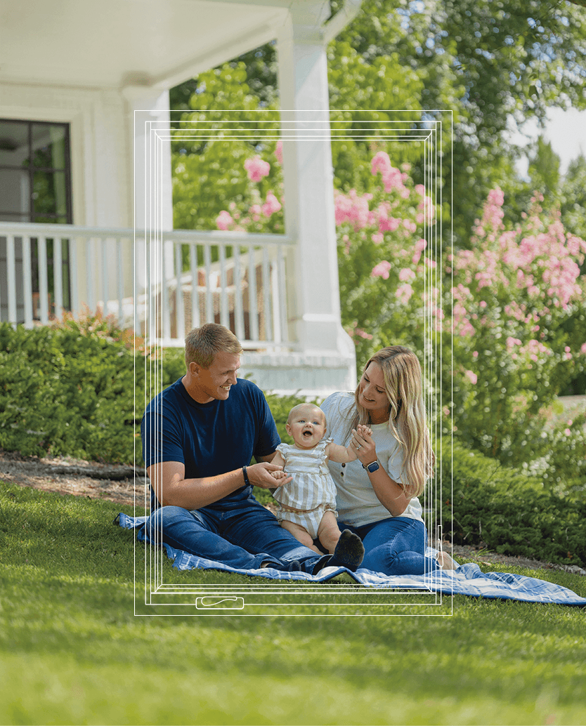 A family sitting together out in their front lawn.