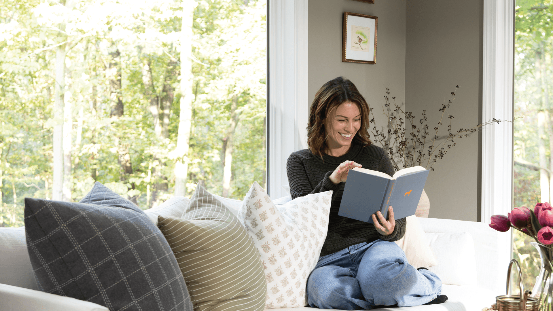 A woman sitting on a couch reading a book.