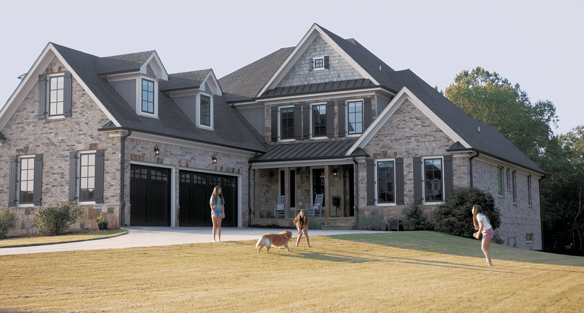 Kids playing in the yard with house behind with infinity from marvin windows in bronze finish